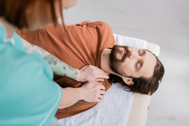 high-angle-view-bearded-man-with-closed-eyes-near-blurred-physiotherapist-doing-shoulder-massage_optimized_100