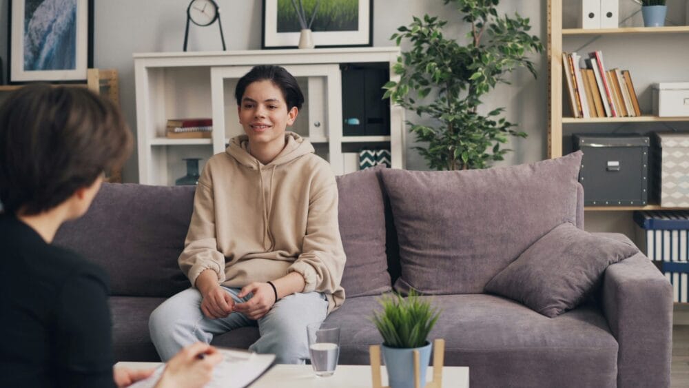 Teen client talking calmly with a therapist during an anger management session