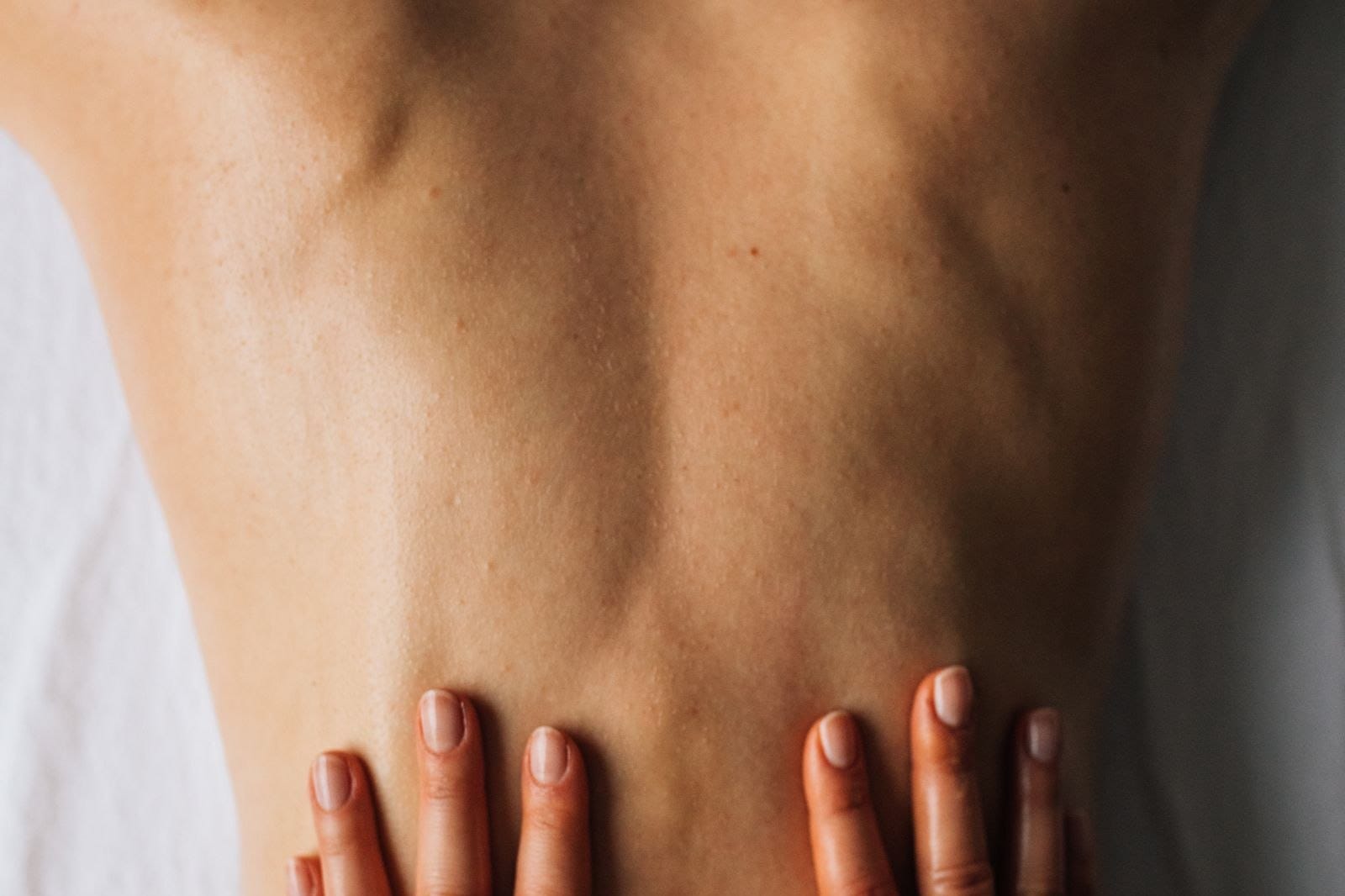 Practitioner's hands on a client's upper back during a cupping treatment